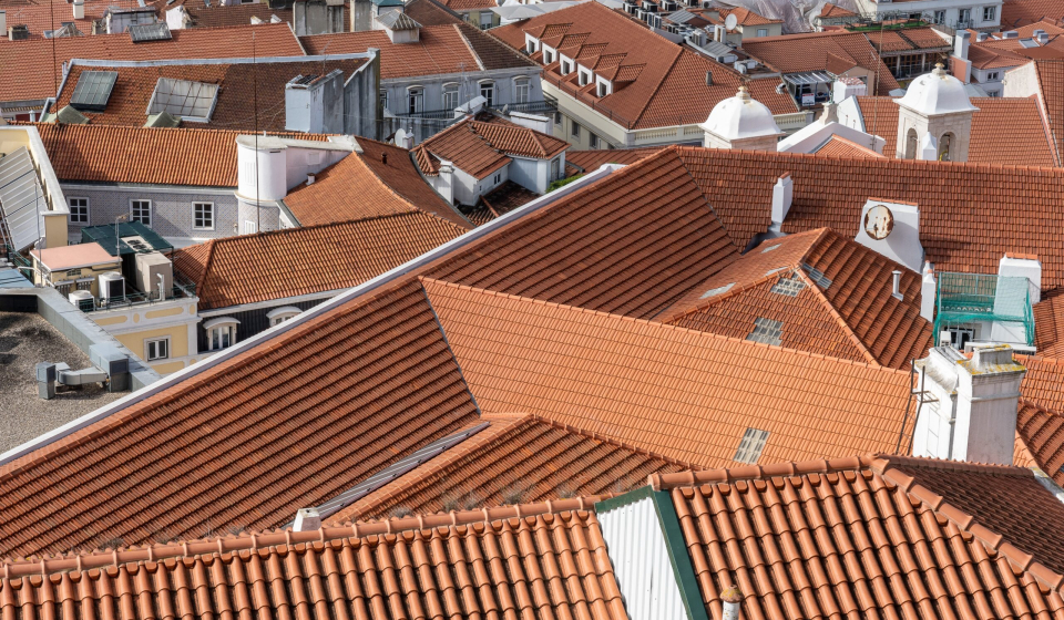 An aerial shot of rooftops of city buildings with red shingles